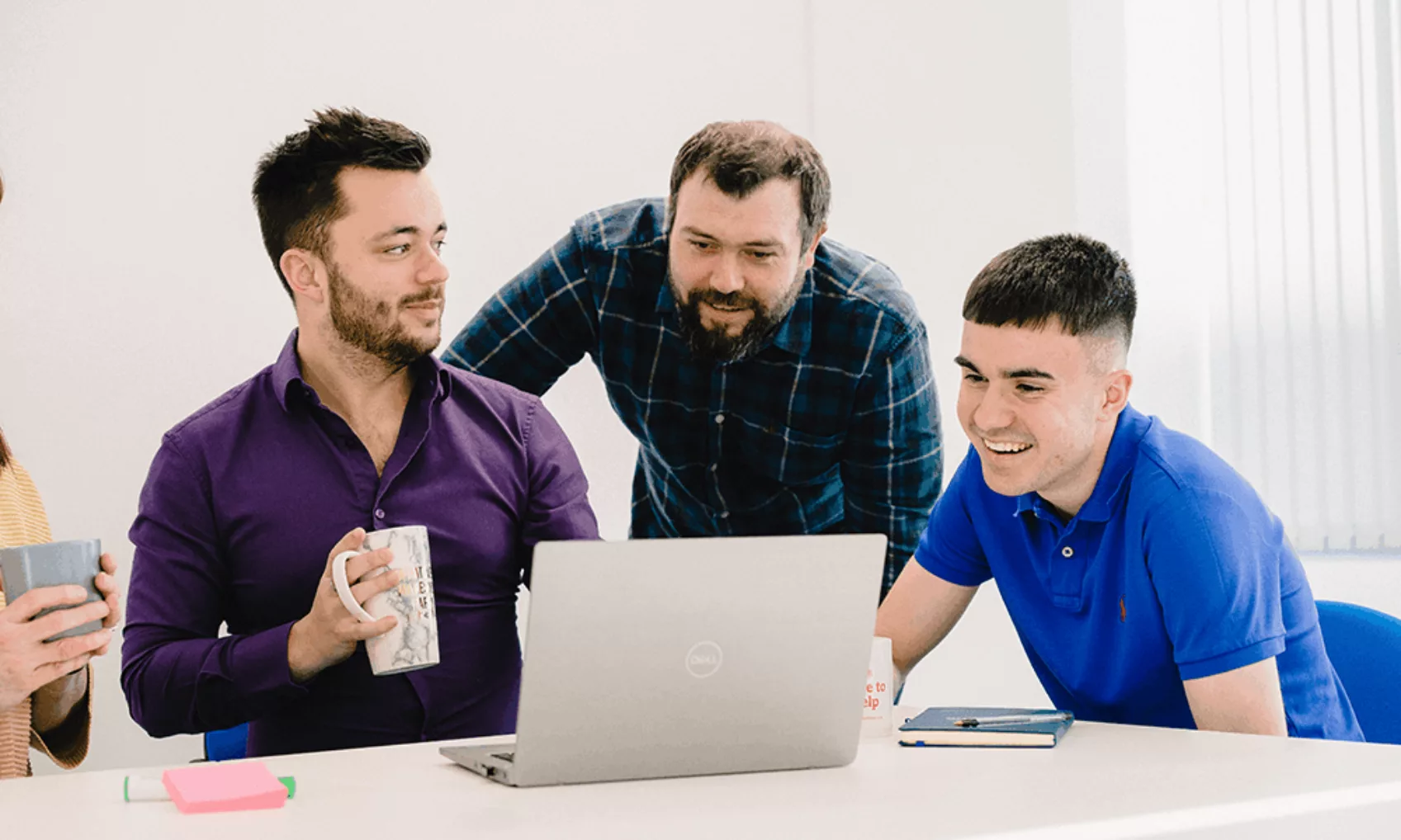 Luke Mitchell gathers around a laptop with his colleagues in the Cardiff office