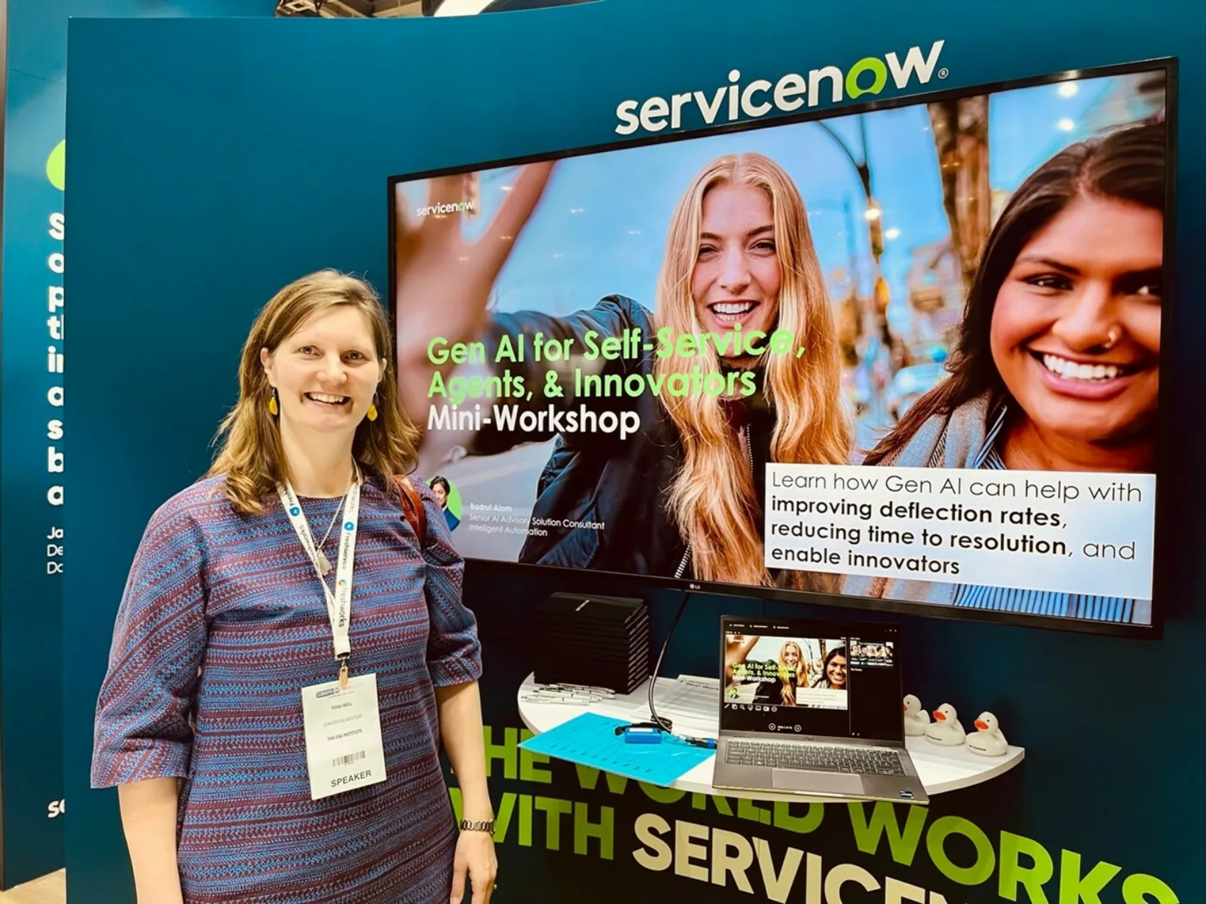 Dr Tuuli Bell stands smiling next to the ServiceNow stand at SITS 2024.