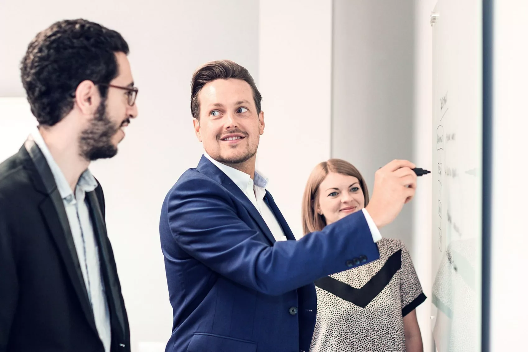 3 team members in discussion around a white board