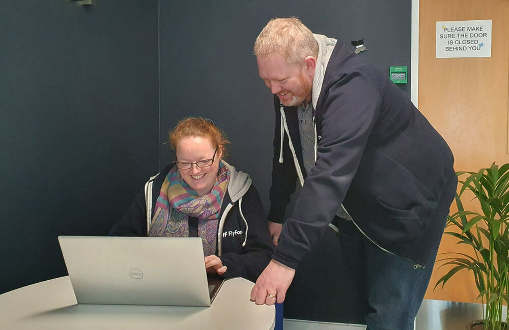 Tom Collis assists Senior PMO Analyst, Becca Callan, with an issue on her laptop in the office.